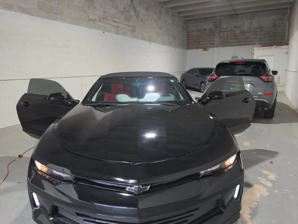 Black Camaro with open doors during a window tinting job in Doral